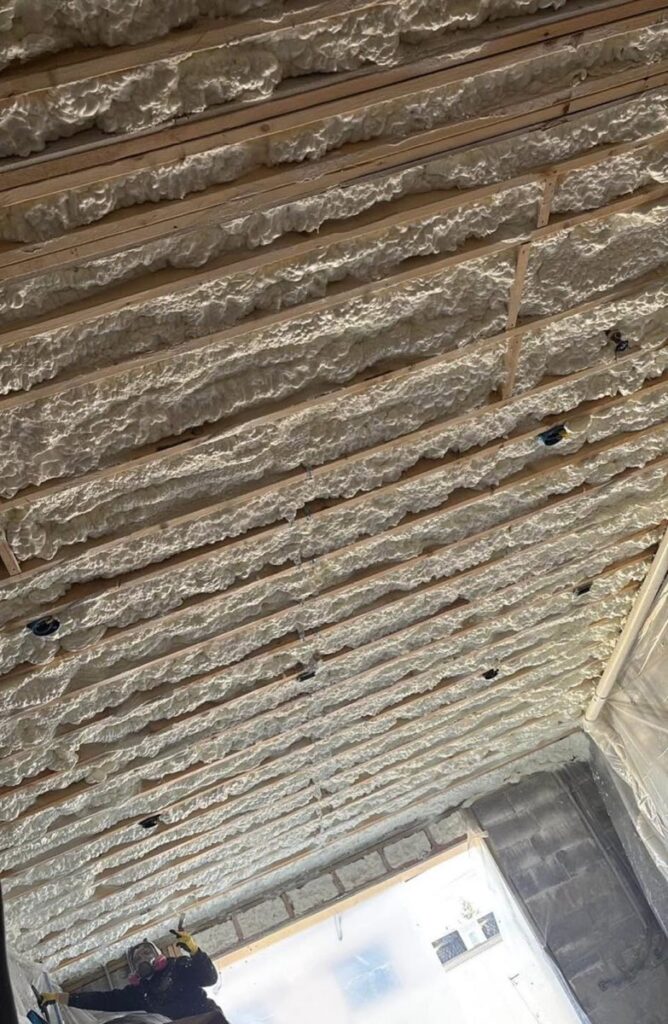 Spray foam applied between the floor joists above a basement