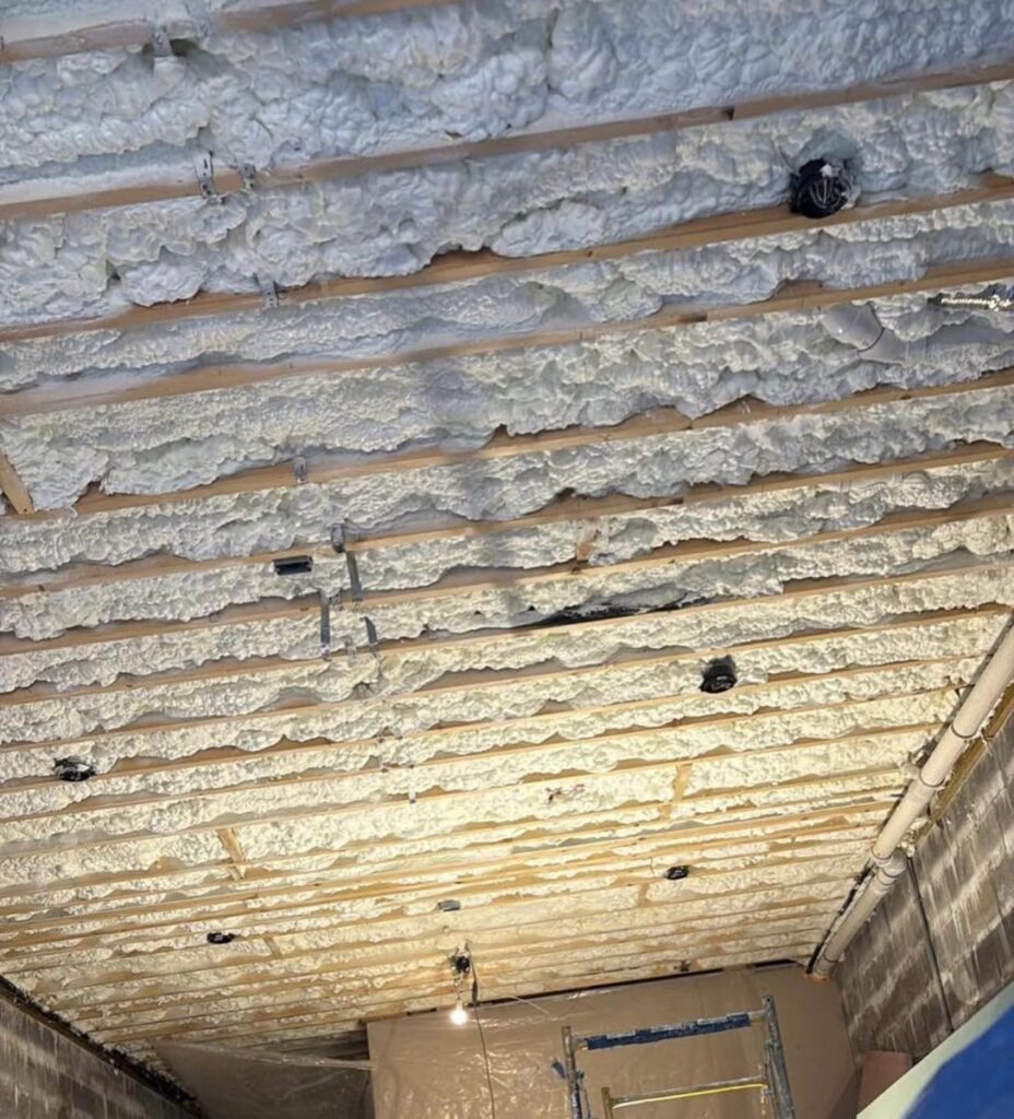 Spray foam sealing basement ceiling joists to stop heat loss through the floor