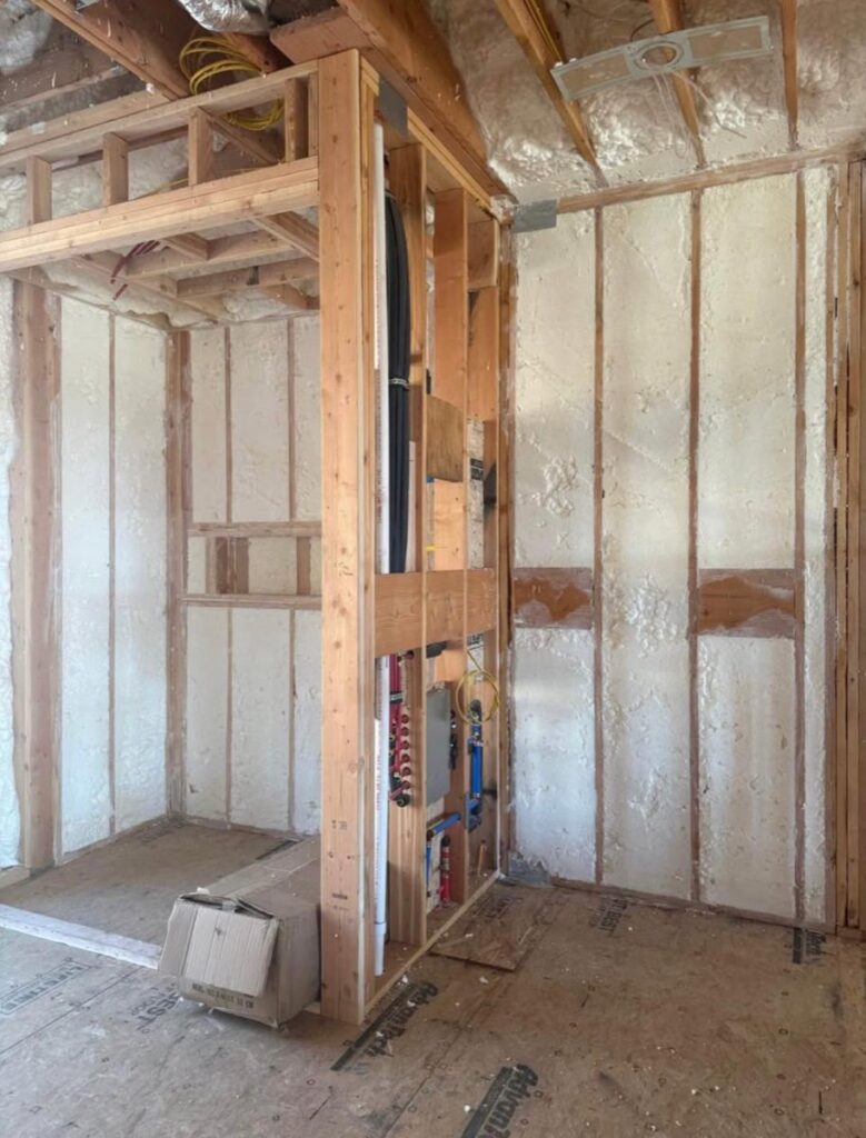 Spray-foamed walls around a plumbing manifold in a new build