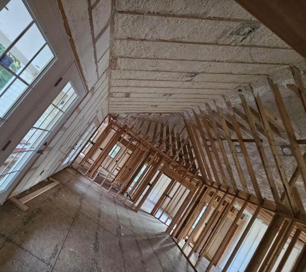 Spray-foamed exterior walls seen across open roof framing